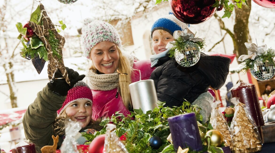 Austria, Salzburg, Mother with children at christmas market, smiling